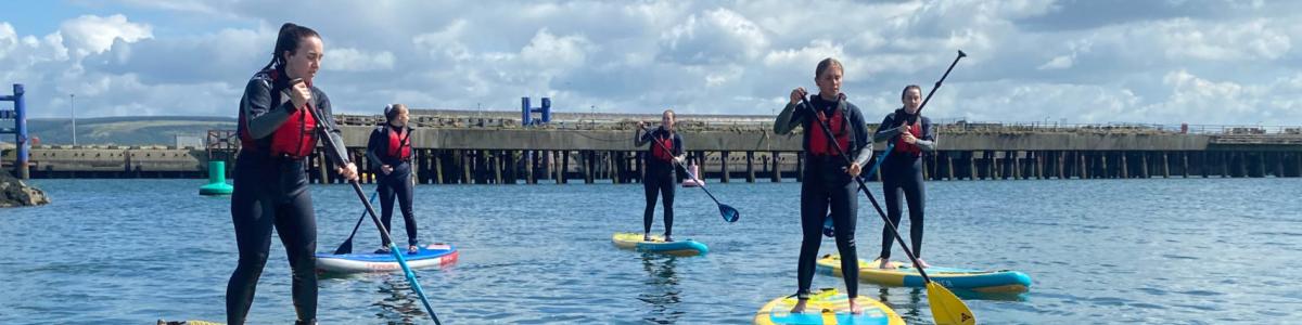 group trying stand up paddle boarding