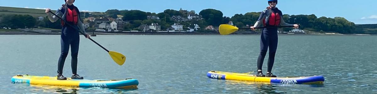 Two girls stand-up paddlleboarding at Loch Ryan